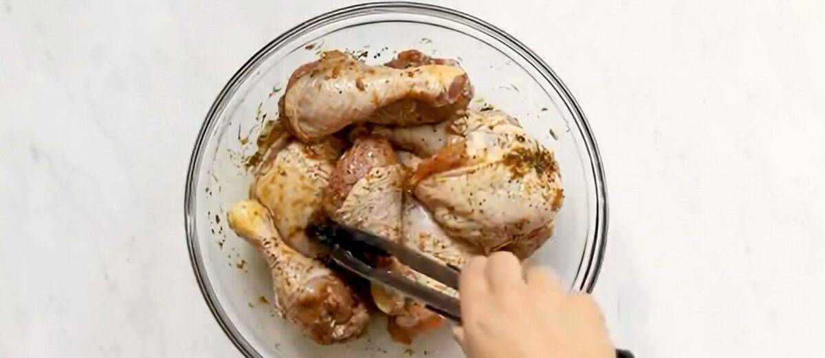 Chicken thighs marinating in a glass bowl.