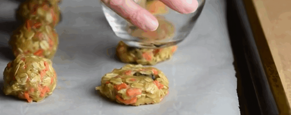 Flattening the cookie dough balls with the bottom of a glass. 
