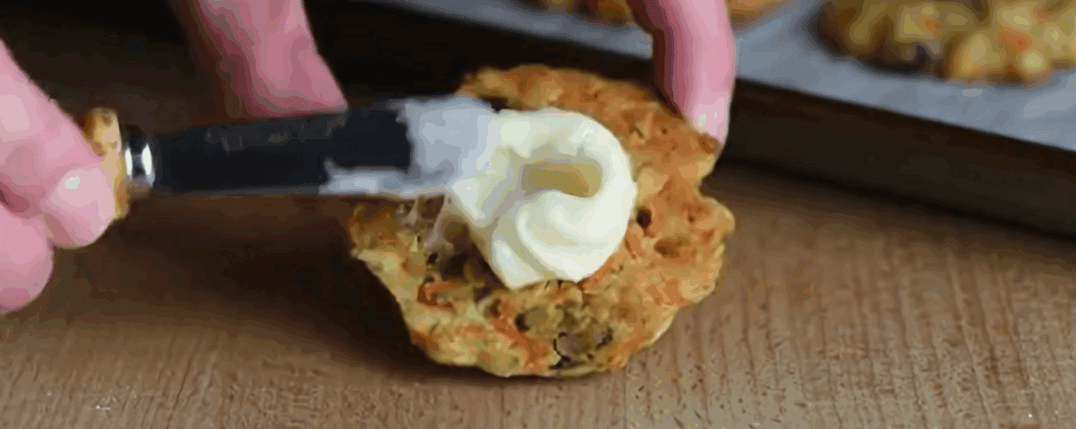 Coating the bottom of a cookie with cream cheese frosting. 