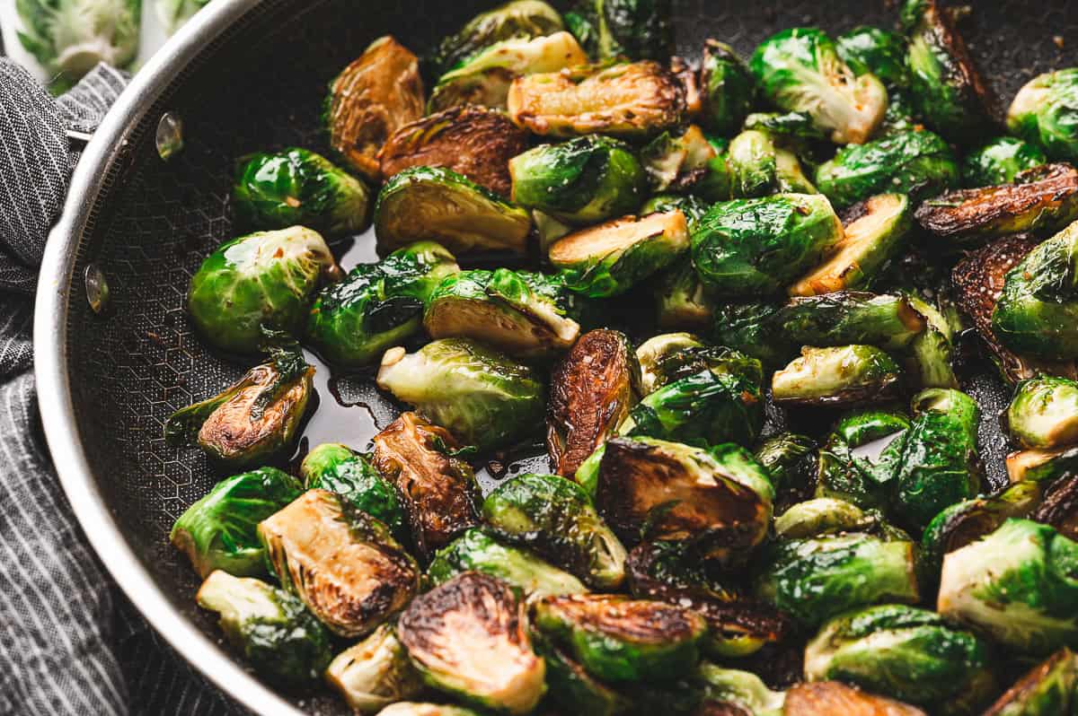 Close-up of sautéed Brussels sprouts in a skillet, caramelized on the cut sides and coated with a glossy molasses glaze.