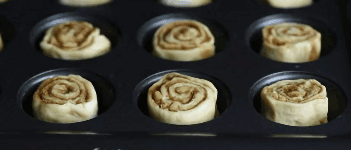 Mini cinnamon rolls in a muffin tray.