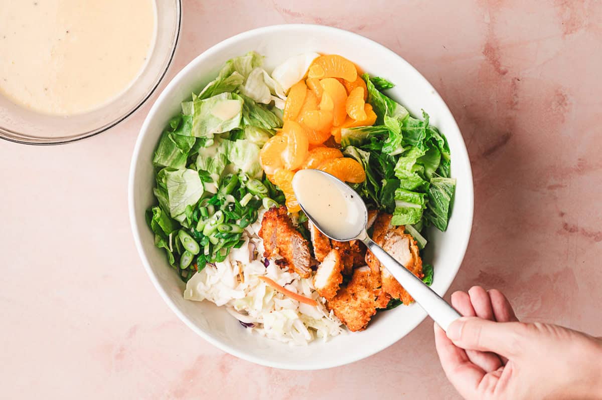 Adding the honey sesame dressing to the salad