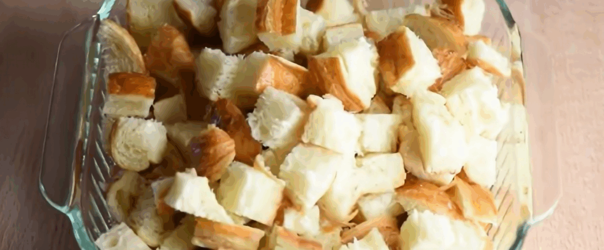 Glass casserole dish with cut up croissants.