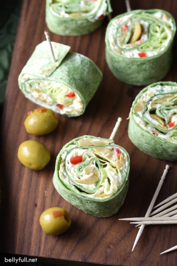 In these Olive Pinwheels, spinach flavored flour tortillas are coated with an olive and cream cheese spread, topped with scallions and lettuce, for an easy crowd-pleasing appetizer, snack, or light lunch!