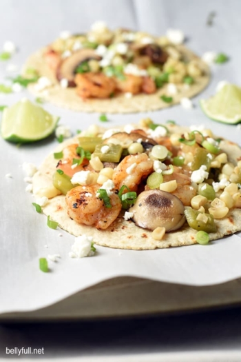 Easy Shrimp Fajitas with corn, mushrooms, poblano peppers, and feta cheese. Everything can be prepared on the grill or in a skillet, so you can make them all year round. Delicious 30 minute meal!