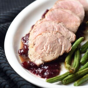 Pork tenderloin is marinated in garlic and cracked black pepper seasonings, then topped with a cranberry-pomegranate sauce and served with roasted green beans. Wonderful and easy 30 minute meal!