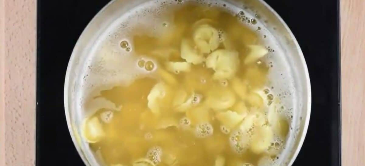 Tortellini boiling in a pot of broth.