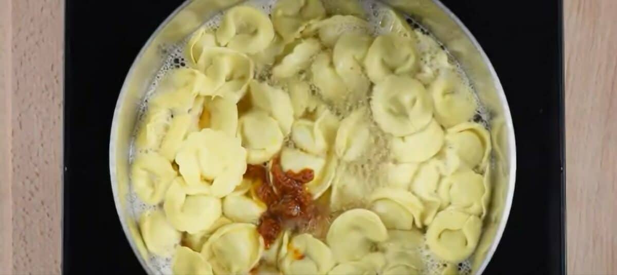 Adding sundried tomato pesto to the pot.