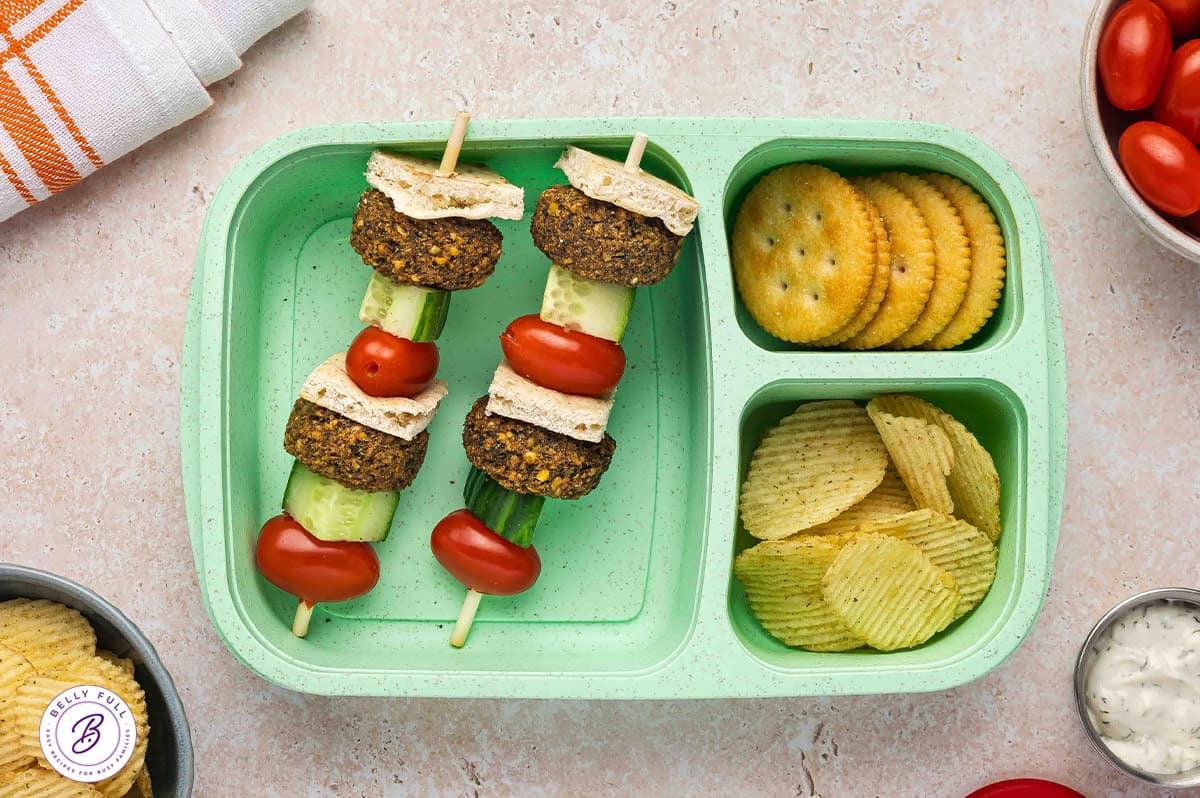 Falafel on a stick with pieces of pita bread, falafel, cucumber, cherry tomatoes, in a lunch box