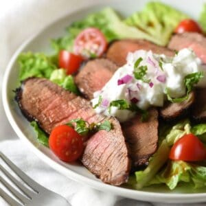 Grilled Steak Salad with Tzatziki Sauce - tender marinated steak is served on top of salad with a light and refreshing yogurt sauce for an easy, low-calorie meal!