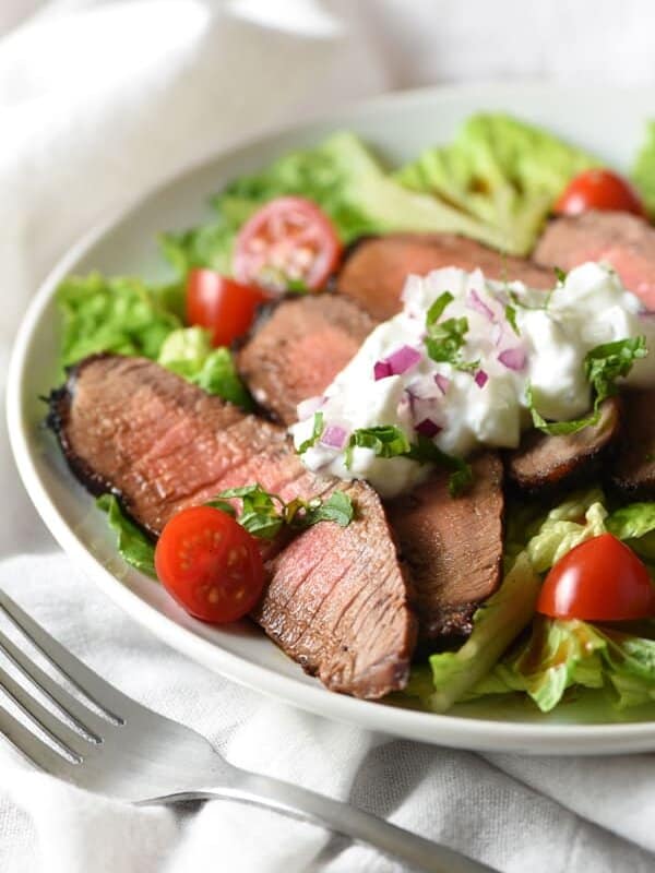 Grilled Steak Salad with Tzatziki Sauce - tender marinated steak is served on top of salad with a light and refreshing yogurt sauce for an easy, low-calorie meal!