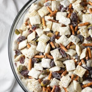 15-minute Chex Mix Muddy Buddies with a Christmas holiday flair, including white chocolate, powdered sugar, pretzels, craisins, and pistachios!