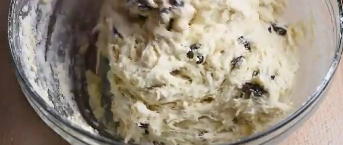 Raw dough with raisins in a glass bowl.