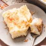 A slice of coconut cream lush on a plate with a fork
