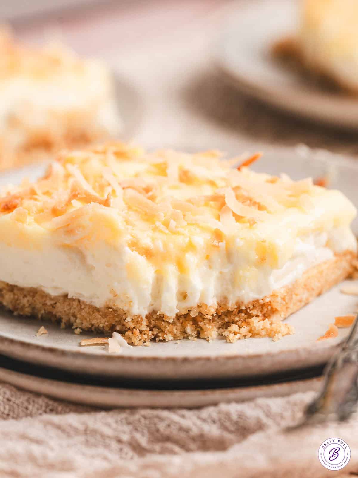 This Coconut Cream Lush is smooth, rich, light, and there’s no cooking involved. It’s so easy and perfect for summer gatherings! A slice of coconut cream lush on a plate