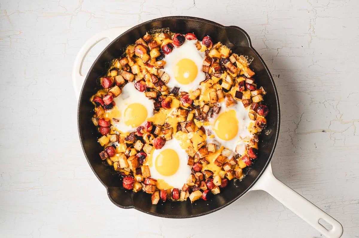 Smoked sausage, diced potatoes, egg, and cheese make this Skillet Breakfast Hash an easy, savory, and hearty breakfast. Eggs in a pan with sausage and potatoes
