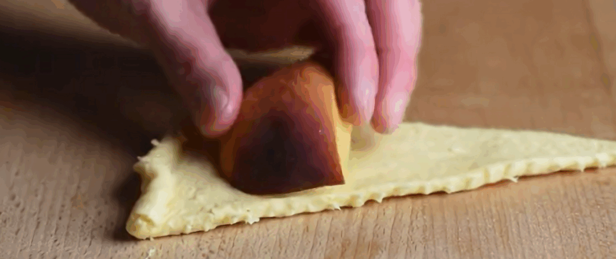 A peach wedge on a triangle of dough. 