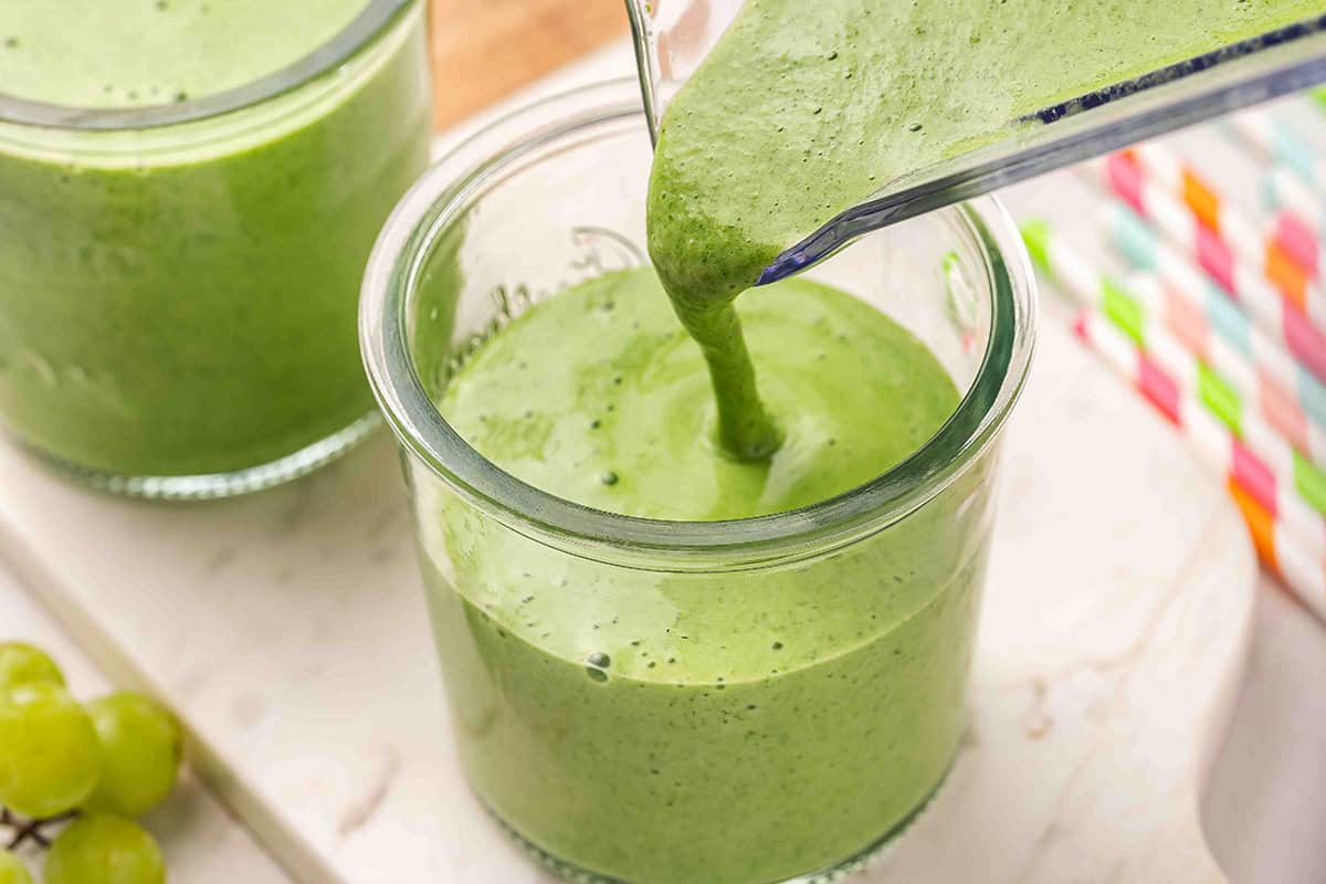 Green smoothie being poured from a blender into a glass
