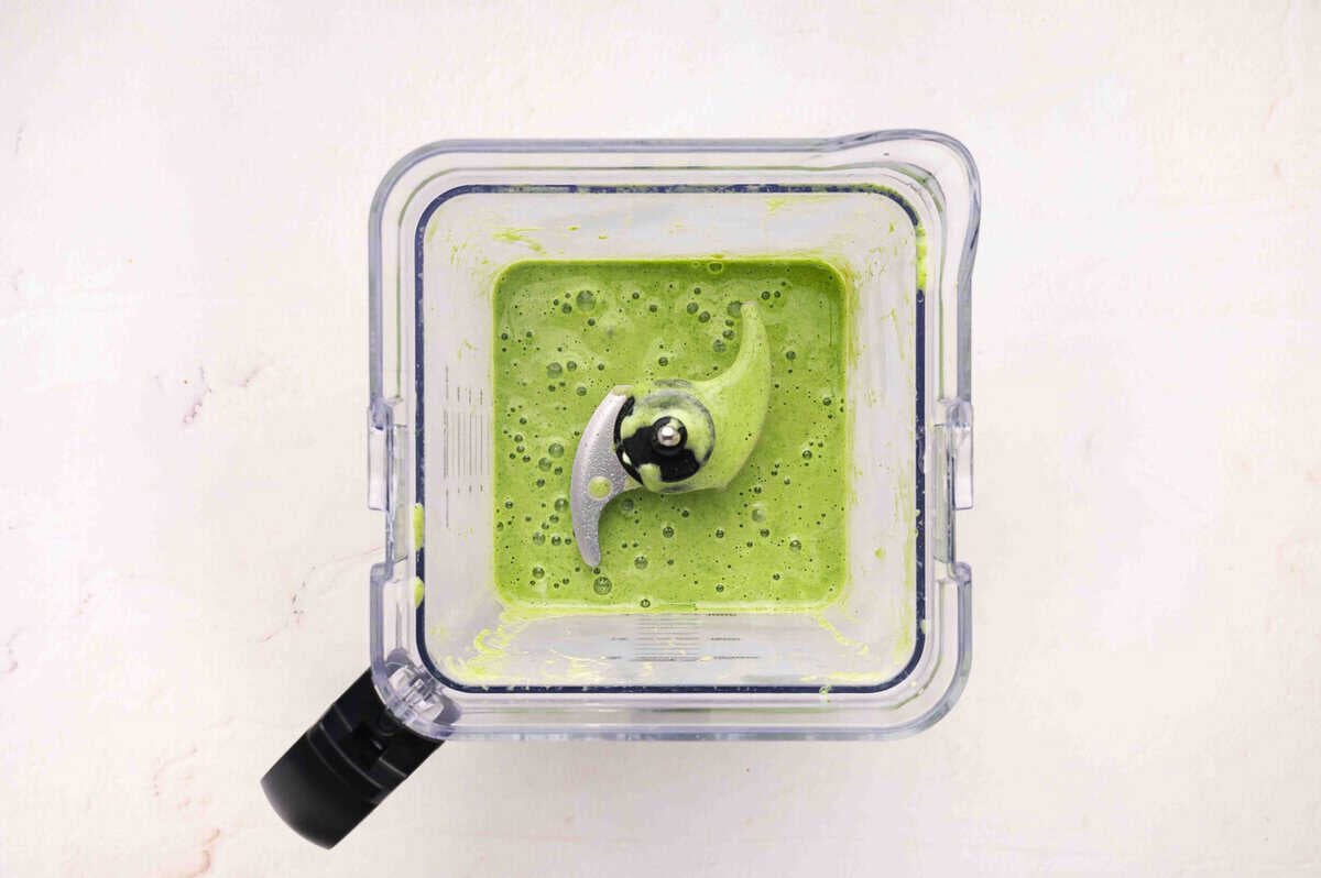 Overhead view of green smoothie blended smooth in a blender, ready to pour into glasses
