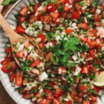 Bowl of fresh pico de gallo with tomatoes, onion, jalapeño, and cilantro, served with a wooden spoon