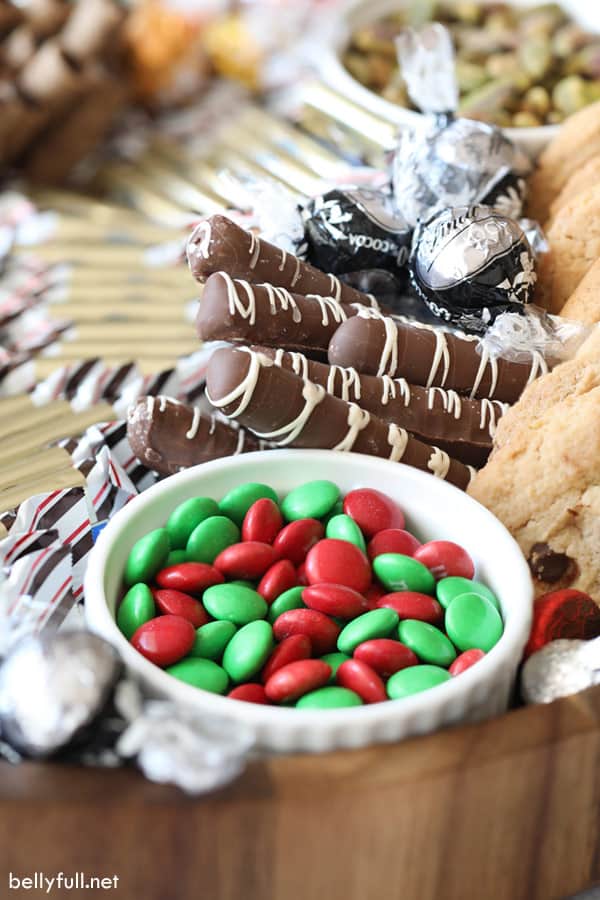 Charcuterie Board with red and green M&Ms, truffles, cookies, and chocolate covered pretzels