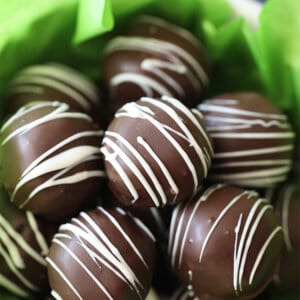 bowl of chocolate Oreo Truffles drizzled with white chocolate with green tissue paper