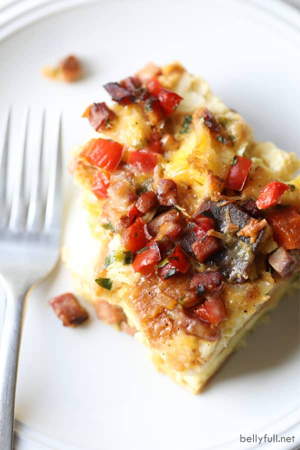 overhead picture of ham breakfast casserole piece on white plate with fork