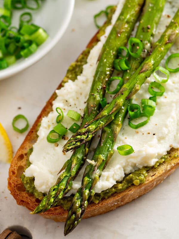 overhead picture of roasted asparagus on toasted bread with pesto and ricotta