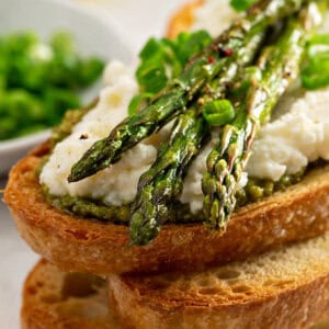 close up picture of roasted asparagus on ricotta and toasted bread