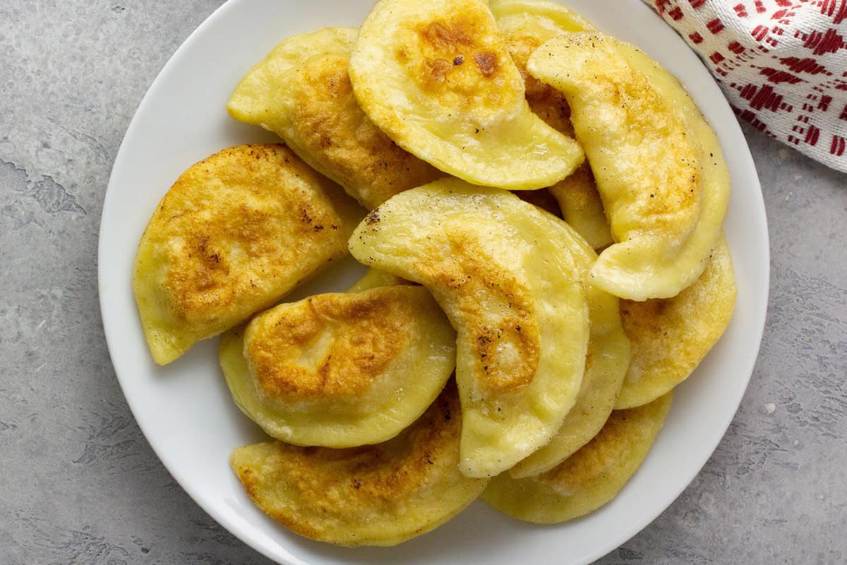 Pan fried pierogi on a white plate.