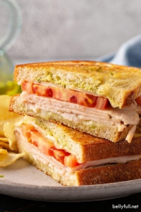 pesto grilled cheese sandwich cut in half and stacked on plate