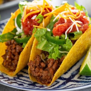 2 crispy tacos on ornate plate topped with lettuce and salsa
