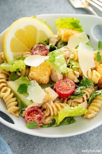 Chicken Caesar Pasta Salad in white dish with a lemon wedge