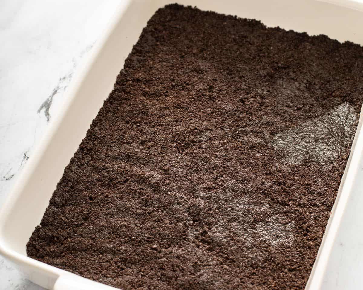 The Oreo cookies pressed into the bottom of a baking pan.