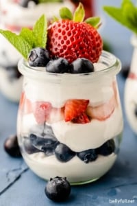 Red White Blue Cheesecake Mousse in parfait glasses with fresh blueberries, strawberries, and mint leaf