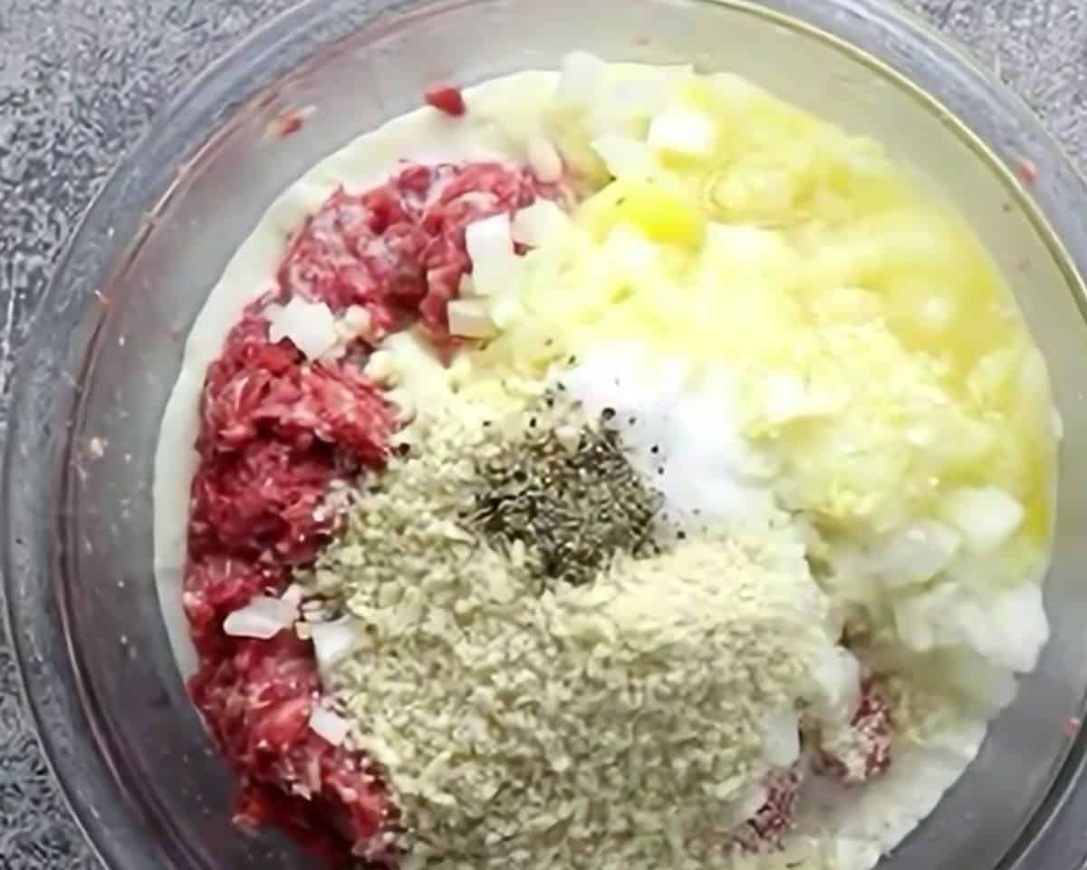 Ingredients to make the meatballs in a glass bowl.