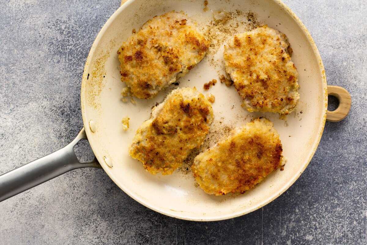 Pan frying breaded pork in a skillet.