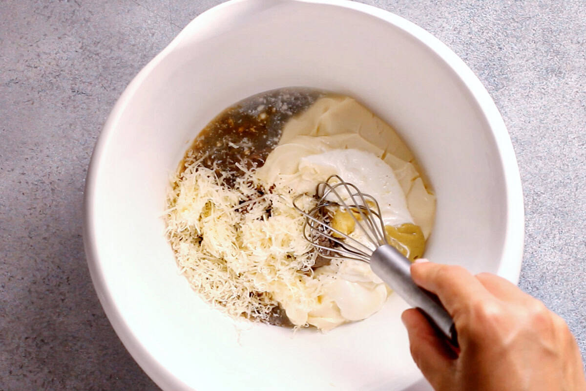 Dressing ingredients being whisked in a white bowl.