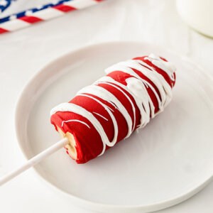 half a frozen banana coated in red chocolate drizzled with white chocolate on a white plate