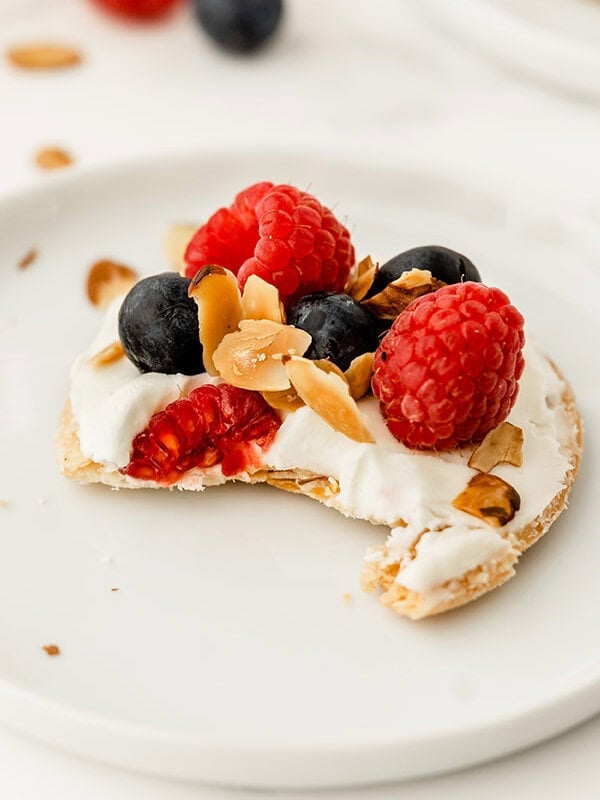 close up of mini raspberry and blueberry fruit tart with bite taken