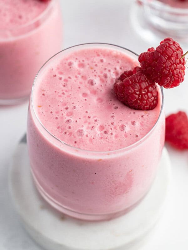 raspberry lassi in glass with fresh raspberries as garnish