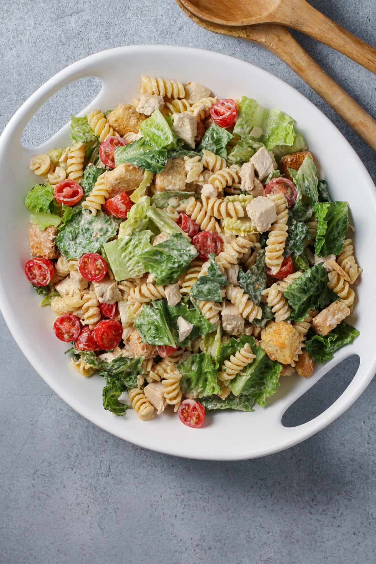 A white platter of chicken Caesar pasta salad.