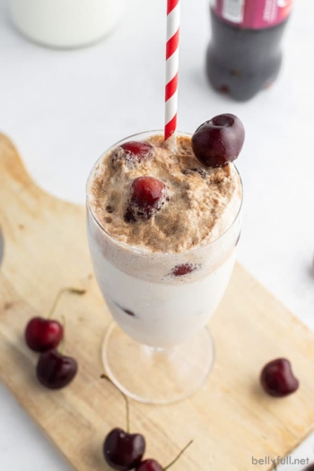 cherry ice cream float in tall glass with frozen cherries on top