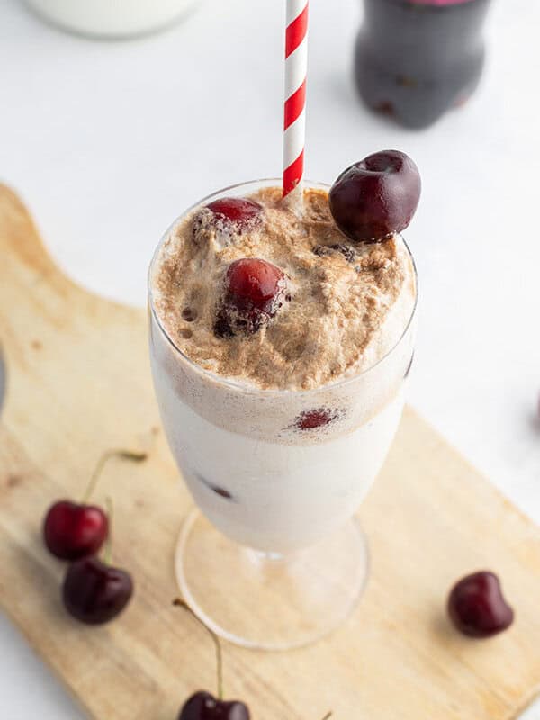 cherry ice cream float in tall glass with frozen cherries on top