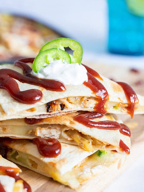 3 stacked quesadilla wedges with barbecue sauce and sour cream