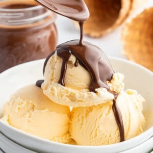 spoon pouring Chocolate Magic Shell on top of vanilla ice cream