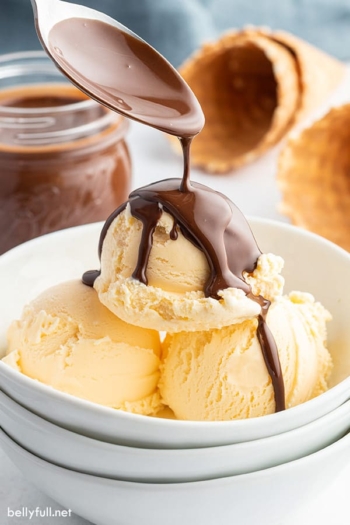 spoon pouring Chocolate Magic Shell on top of vanilla ice cream