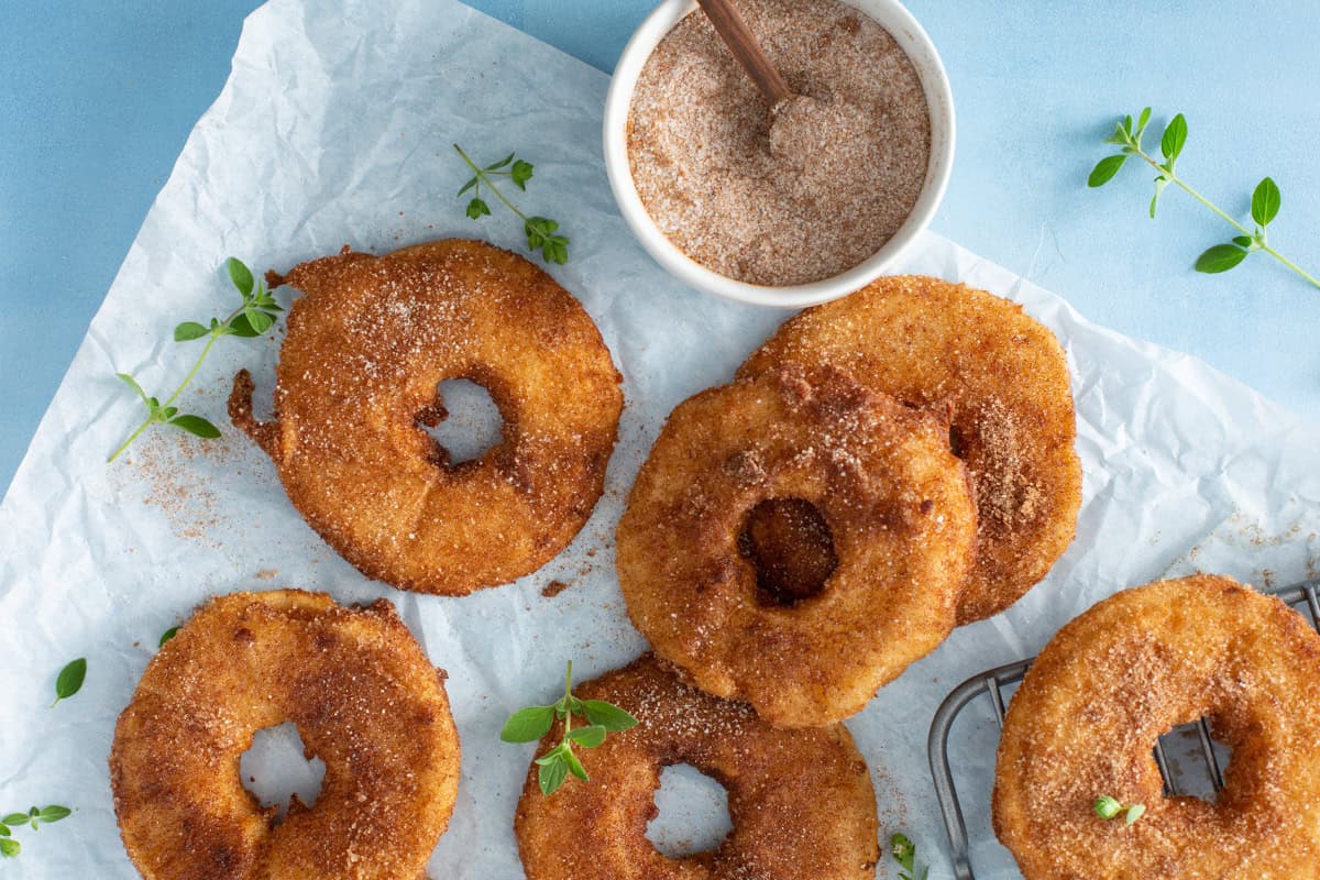 Pineapple fritter rings with a bowl of cinnamon sugar.