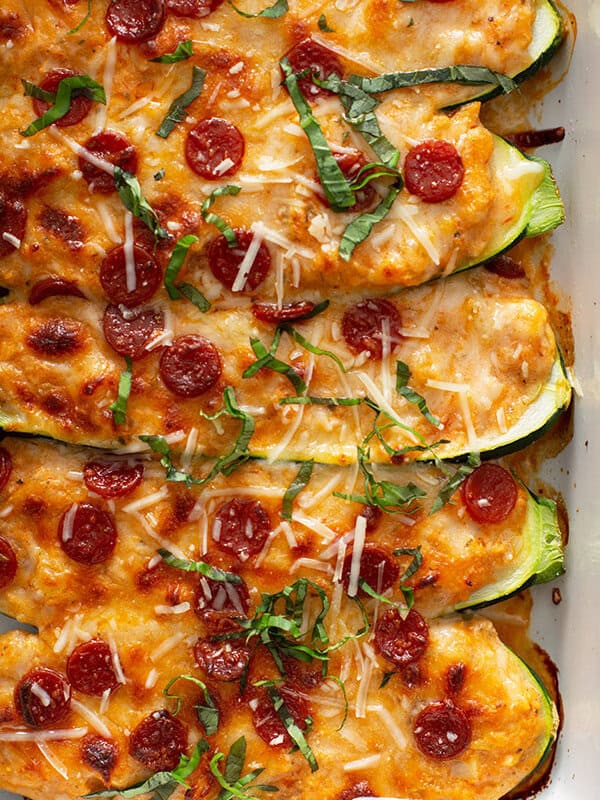 close up of 5 baked zucchini halves stuffed pizza toppings