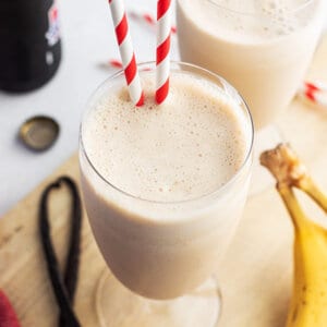 banana smoothie in glass with two straws